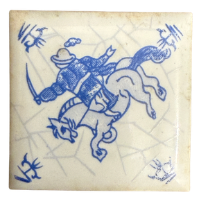 Quadratische Fliese mit blauer Malerei eines Reiters auf sprengendem Pferd mit Säbel, Spinnkopf-Eckmotive, feines Craquelé; daneben gerippte weiße Rückseite und Pappschachtel mit Aufschrift a. Driessen Rotterdam Holland