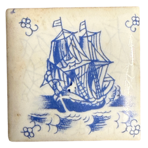 Quadratische Miniaturfliese 4 x 4 cm mit blau gemaltem Dreimaster, Anker und Wellen sowie Blüteneckmotiven auf weißer Glasur; Rückseite mit Pressrippen, dazu Schachtel A. Driessen Rotterdam